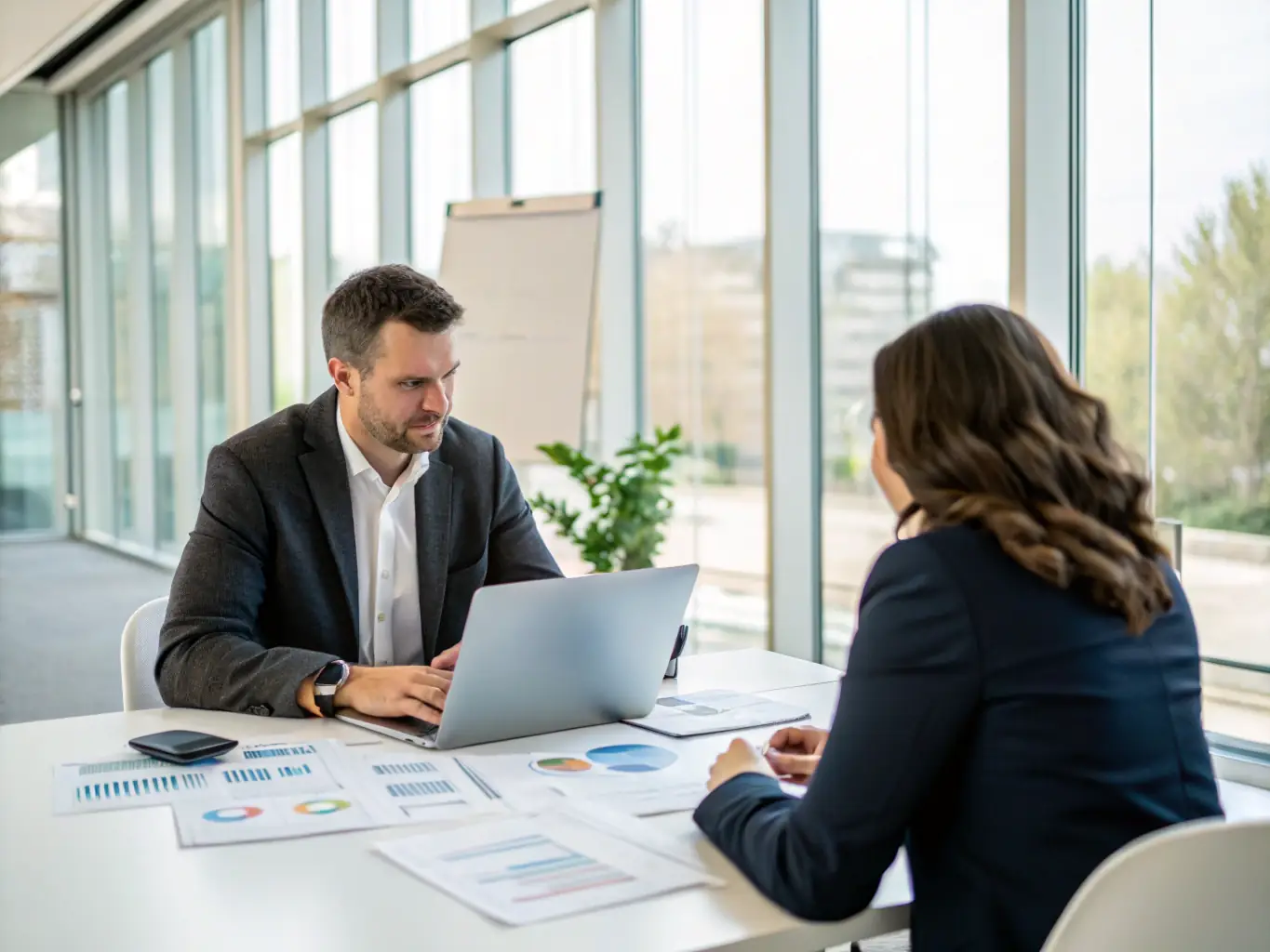 A professional business coach is guiding a client through a bidding strategy document in a modern office setting, emphasizing collaboration and strategic planning.
